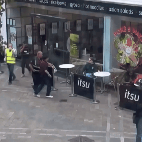 A Group Of People Standing Outside Of A Restaurant Called Jitsu GIF