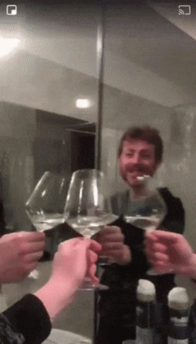 A Group Of People Toasting With Wine Glasses In Front Of A Mirror With A Square In The Corner GIF
