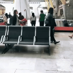 A Group Of People Walking Around A Waiting Area GIF