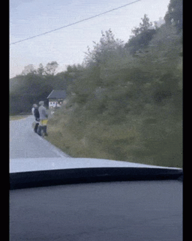 a group of people walking down a road with a small house in the background