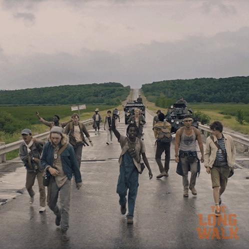 A Group Of People Walking Down A Road With The Long Walk Written On The Bottom Right GIF