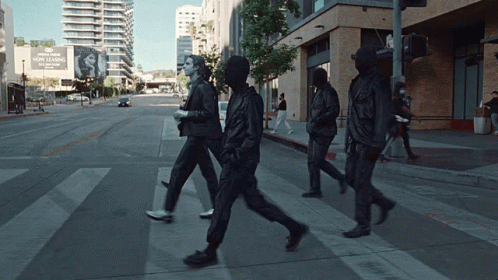 A Group Of People Walking Down A Street In Front Of A Sign That Says ' Now Leasing ' GIF