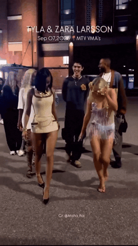 A Group Of People Walking Down A Street With The Words Tyla & Zara Larsson Written On The Bottom GIF