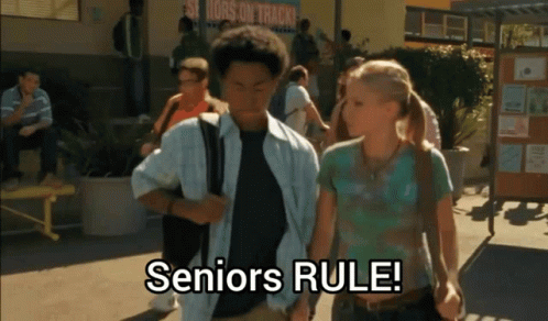 A Group Of People Walking In Front Of A Sign That Says " Seniors Rule " GIF