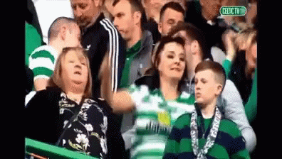 A Group Of People Watching A Soccer Game With A Sign That Says Celtic Tv GIF