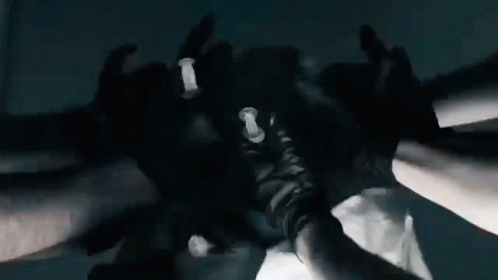 a group of people wearing black gloves are putting their hands together in a huddle .