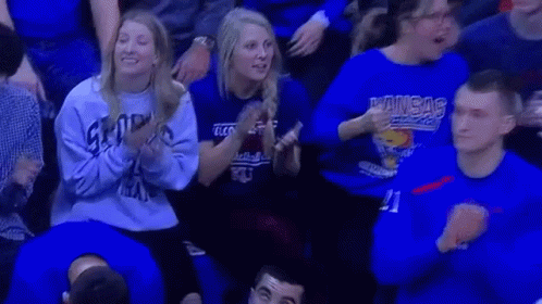 A Group Of People Wearing Blue Shirts Are Sitting In A Stadium Watching A Game . GIF