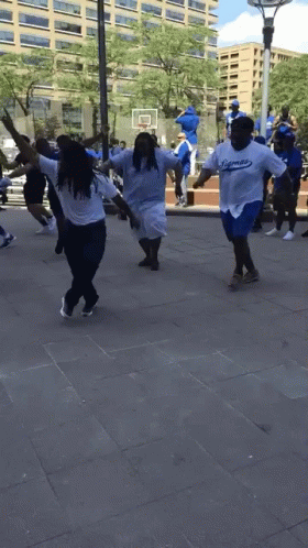 A Group Of People Wearing Dodgers Shirts Are Dancing On The Sidewalk GIF