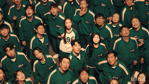 A Group Of People Wearing Green Uniforms With Numbers On Them Are Looking Up GIF