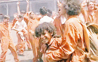 A Group Of People Wearing Orange Jumpsuits Are Standing In A Crowd . GIF