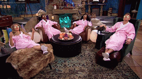A Group Of People Wearing Pink Bathrobes Are Sitting In A Living Room GIF