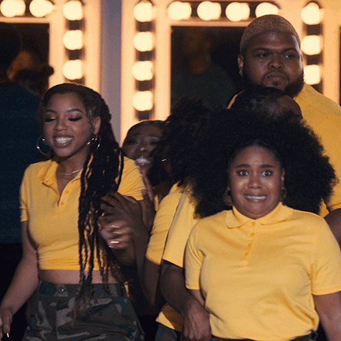 A Group Of People Wearing Yellow Shirts Are Standing Together GIF