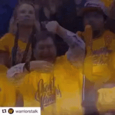 A Group Of People Wearing Yellow Shirts Are Watching A Game . GIF