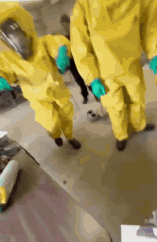 A Group Of People Wearing Yellow Suits And Gloves GIF