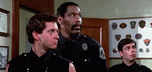 Police Officers Standing In Room Looking At Something GIF