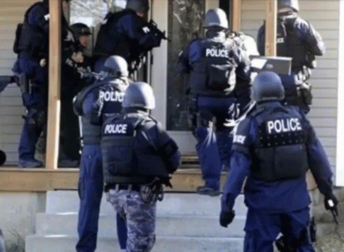 A Group Of Police Officers Are Standing Outside A House GIF