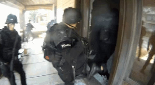 A Group Of Police Officers Entering A Building GIF