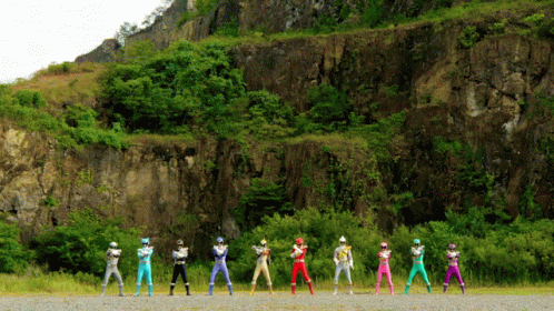 A Group Of Power Rangers Are Lined Up In Front Of A Rocky Hillside GIF
