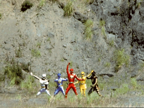 A Group Of Power Rangers Are Standing In A Field With A Mountain In The Background GIF