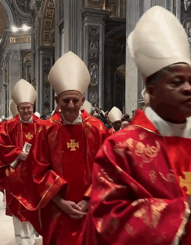 a group of priests are walking in a church and one of them has a cross on his vest
