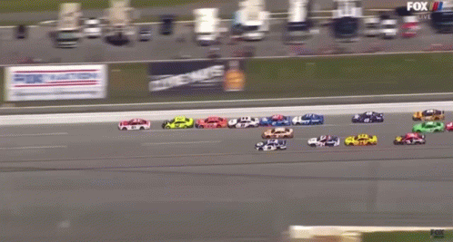 A Group Of Race Cars Are Racing On A Track With A Fox Live Advertisement Behind Them GIF