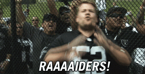 A Group Of Raiders Fans Are Behind A Chain Link Fence And One Of Them Is Wearing A Number 23 Jersey GIF