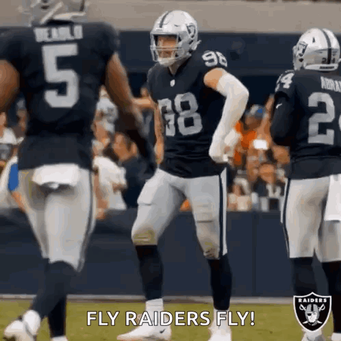 A Group Of Raiders Football Players Are Standing On A Field During A Game . GIF