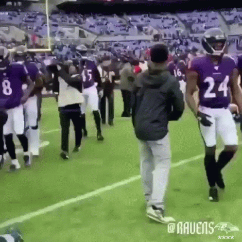 A Group Of Ravens Players Are Walking On The Field GIF