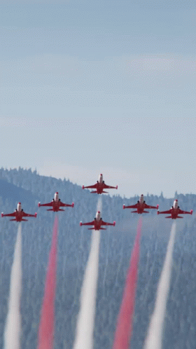A Group Of Red Jets Flying In Formation With Smoke Trails GIF