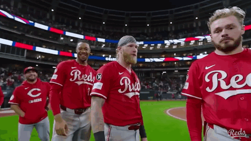 A Group Of Reds Baseball Players Are Standing On The Field . GIF