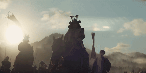 a group of samurai riding horses with a flag in the background
