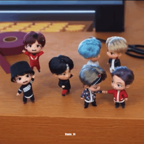 A Group Of Small Dolls Are Standing On A Wooden Table . GIF