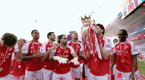 A Group Of Soccer Players Are Celebrating With A Trophy On A Field . GIF