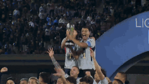 A Group Of Soccer Players Are Holding Up A Trophy In The Air GIF