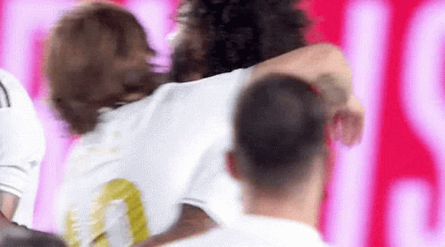 A Group Of Soccer Players Are Hugging Each Other In A Stadium . GIF