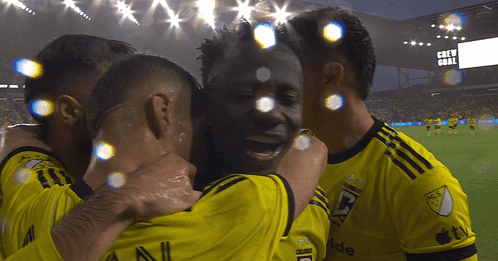 A Group Of Soccer Players Are Hugging Each Other In Front Of A Scoreboard That Says " Crew Goal " GIF