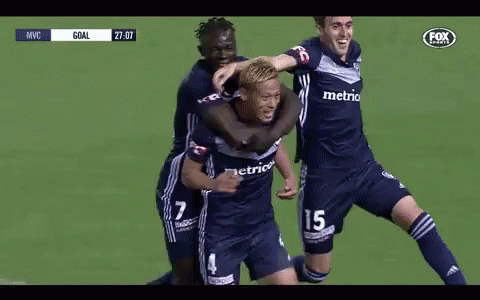 a group of soccer players are hugging each other on a field .