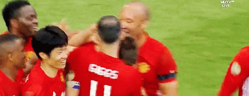 A Group Of Soccer Players Are Hugging Each Other On A Field With Mutv Live In The Background GIF