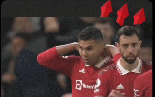 a group of soccer players are hugging each other with one wearing a shirt that says ' united ' on it