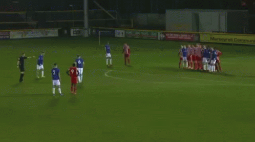A Group Of Soccer Players Are Playing A Game On A Field With A Goal In The Background . GIF
