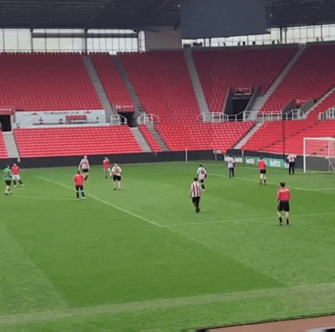 a group of soccer players are playing on a field in front of empty stands