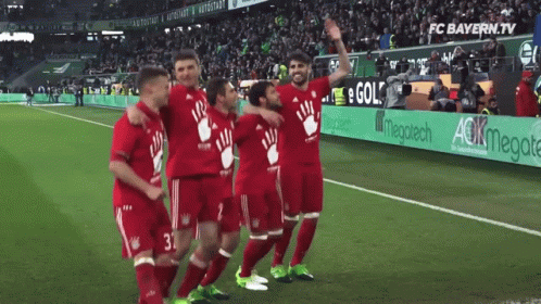A Group Of Soccer Players Are Posing For A Picture On A Field With An Ad For Fc Bayern.tv In The Background GIF