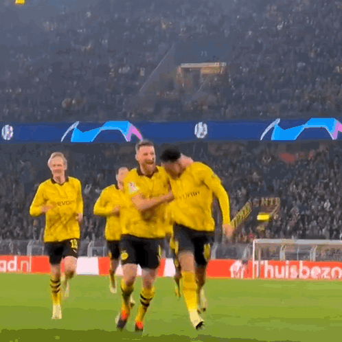 a group of soccer players are running on a field in front of a banner that says ' huisbet '