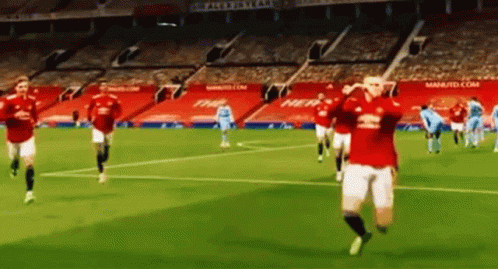 A Group Of Soccer Players Are Running On A Soccer Field In A Stadium . GIF