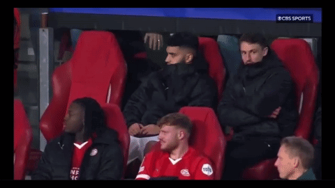 a group of soccer players are sitting in a stadium watching a game on cbs sports .