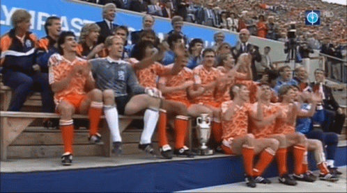 A Group Of Soccer Players Are Sitting On A Bench With A Trophy GIF