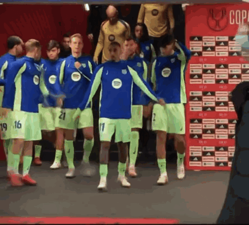 A Group Of Soccer Players Are Standing In Front Of A Red Wall That Says Copa GIF