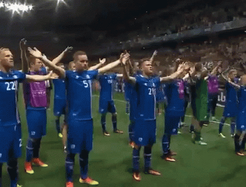 A Group Of Soccer Players Are Standing On A Field With Their Arms Outstretched And One Has The Number 21 On His Shirt GIF