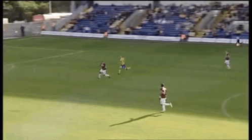 A Group Of Soccer Players On A Field With A Blue Bleacher In The Background GIF
