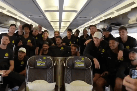 A Group Of Soccer Players Pose For A Picture On A Plane With A Seat That Says " Official Home Of Soccer " On It GIF